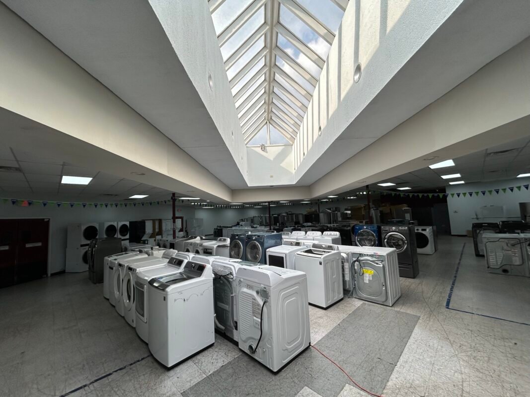 Inside the DMV Appliances Outlet showroom in Alexandria, VA, with rows of washers and dryers under a large skylight